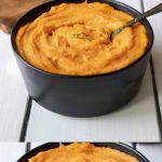 A black bowl filled with roasted carrot and parsnip puree with a spoon