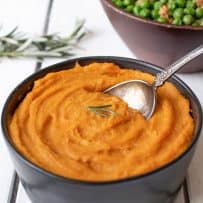 A serving spoon in a bowl full of roasted carrot and parsnip puree