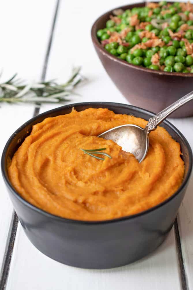 A serving spoon in a bowl full of roasted carrot and parsnip puree