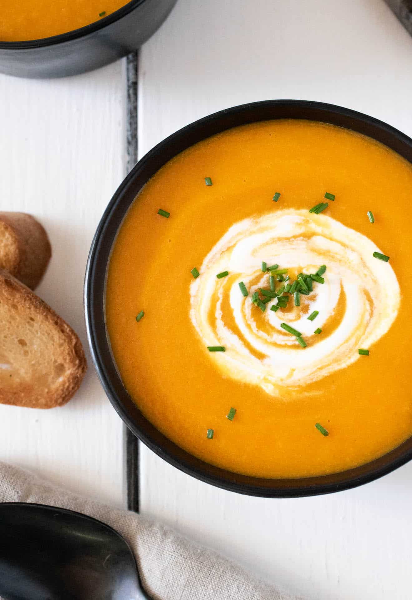 A closeup of the sour cream swirled in the soup and chopped chives
