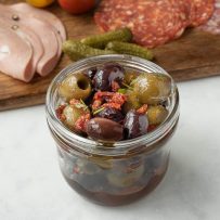 A jar full of olives, sun-dried tomato and rosemary
