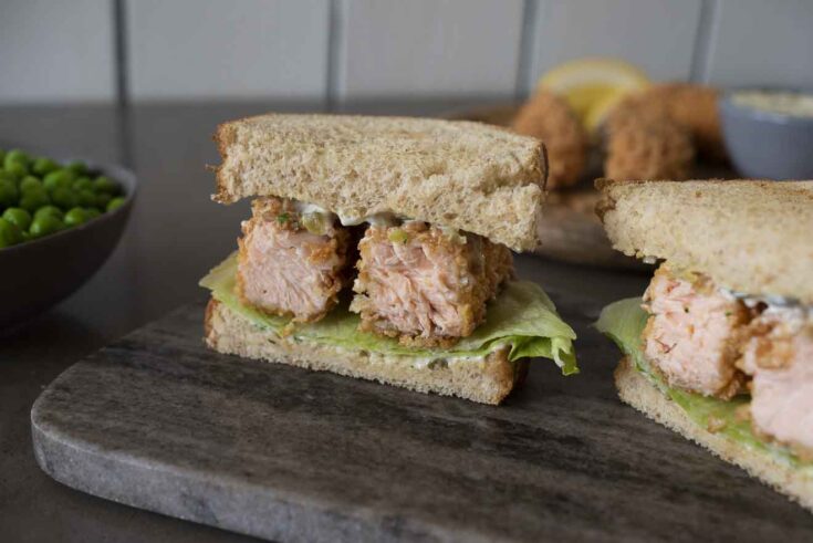 A closeup of a salmon fish finger/fish stick sandwich cut so you can see the inside of the salmon