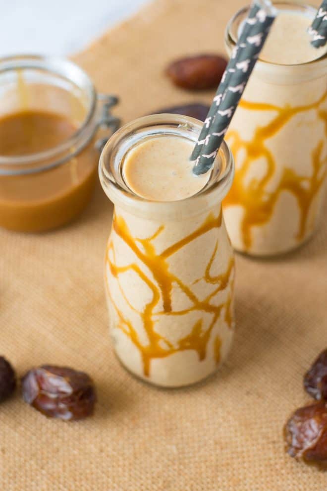 A milk bottle filled with salted caramel date shake with caramel drizzled on glass