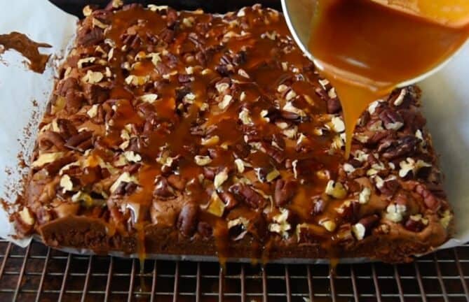 Drizzling caramel sauce over pecan brownies