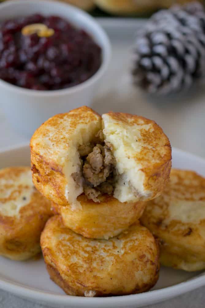 Sausage stuffed potato dumplings on a white serving plate with 1 cut open