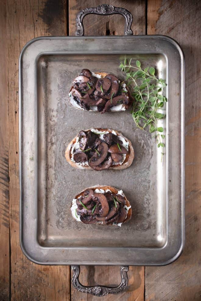 A silver serving tray with saut&eacute;ed mushroom and rosemary bruschetta