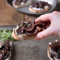 Holding a sautéed mushroom and rosemary bruschetta