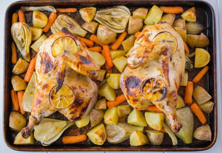 Two halves of a chicken and vegetables on a sheet pan