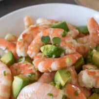 A bowl of cooked shrimp and chopped avocado