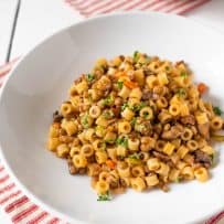 A closeup showing the round ditalini pasta mixed with the lentil sauce served on a white plate