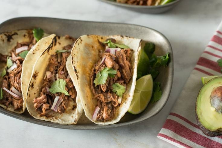Shredded beef in a soft taco served with fresh cilantro