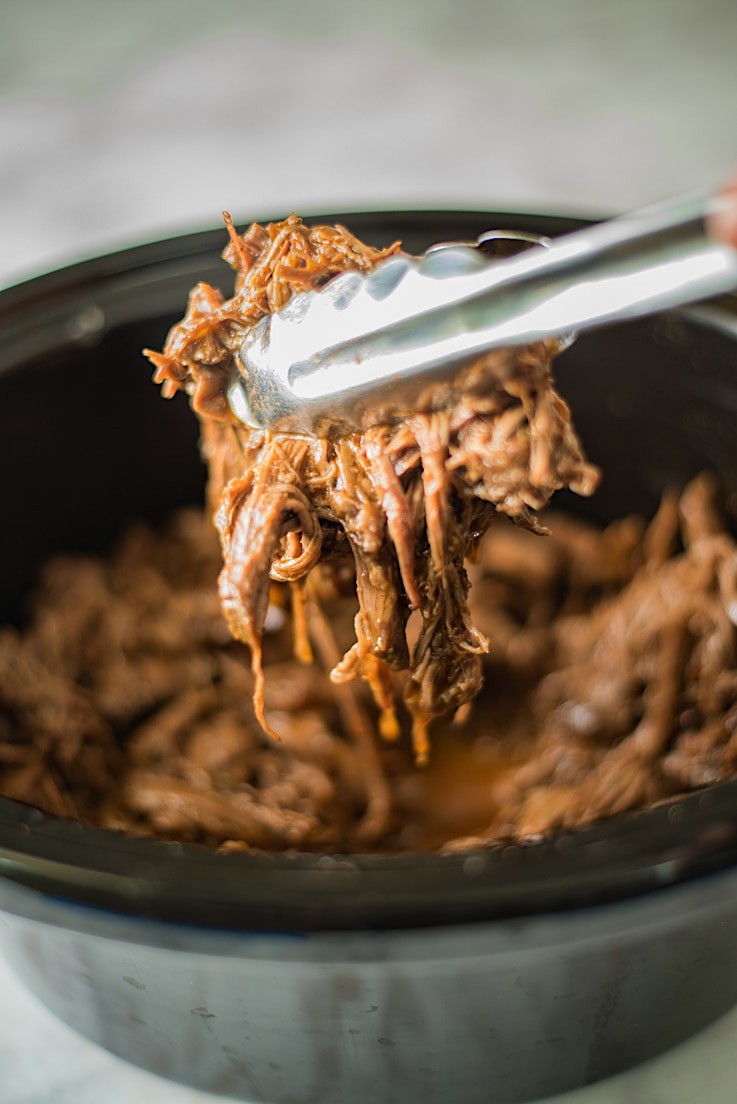 Grabbing shredded beef with tongs