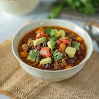 Slow cooker beef and sweet potato chili served in a white bowl with a spoon
