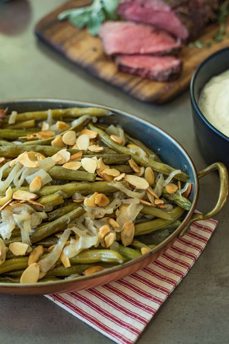 A closeup of the green beans in a serving dish showing the almonds and shallots