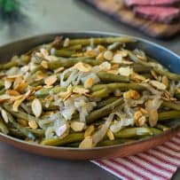 A copper serving dish filled with slow cooker green beans