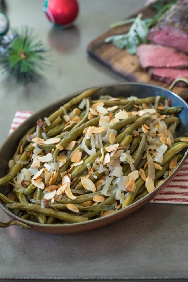 An oval serving dish of slow cooker green beans with shallots and almonds