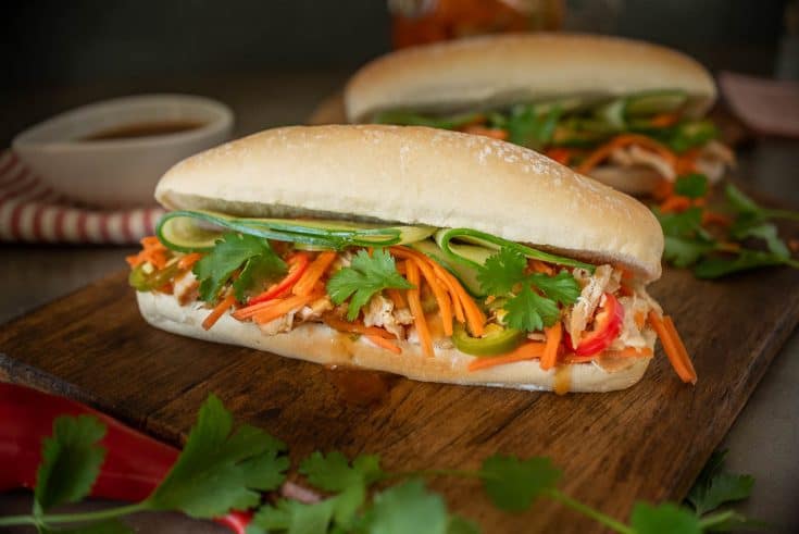 A soft roll is filled with shredded chicken, carrot slaw, cucumber and cilantro