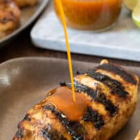 Jalapeño lime sauce being drizzled on top of grilled chicken