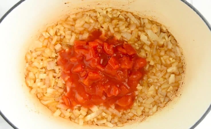 Cooked onions and garlic with diced tomatoes in a pan