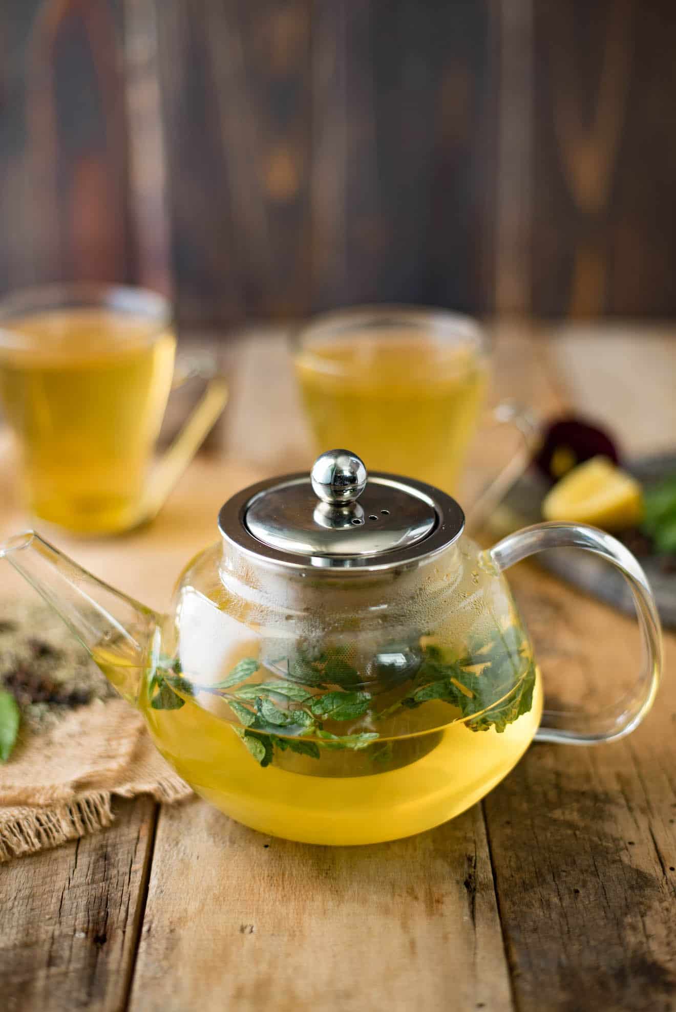 Fresh mint in a glass teapot of herbal tea with cups