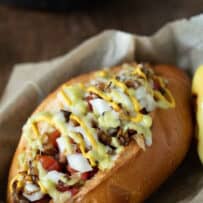 Jalapeno sauce, mayonnaise, mustard, onions, tomato and pinto beans piled on top of a hot dog in a bun