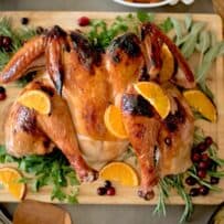 A spatchcock roasted turkey garnished with herbs and orange slices.