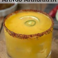 A spice rimmed glass filled with vibrant yellow mango margarita