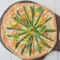 Spring vegetable pizza with colorful vegetables on a pizza board with a pizza cutter