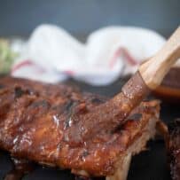 Brushing barbecue sauce over ribs