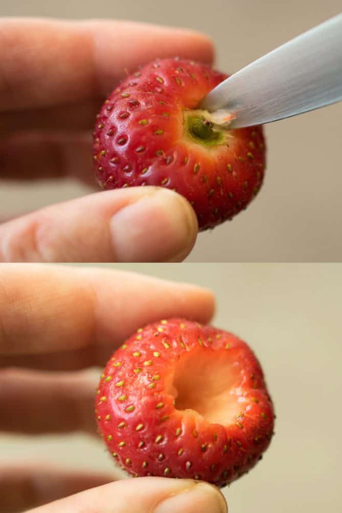 A closeup showing a knife cutting out the hull/stem of a strawberry