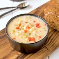 A creamy bowl of corn chowder served with sliced bread