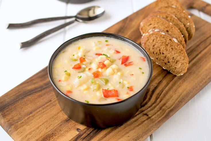 A creamy bowl of corn chowder served with sliced bread