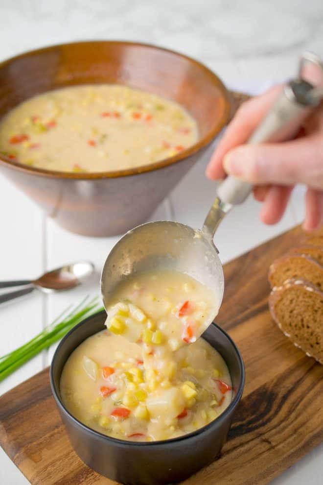 Using a ladle to spoon Summer Corn Chowder into a bowl