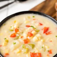 A closeup of colorful red peppers and celery in corn chowder with potato