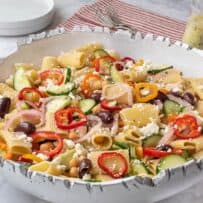 A bowl of pasta salad with vegetables and cheese.