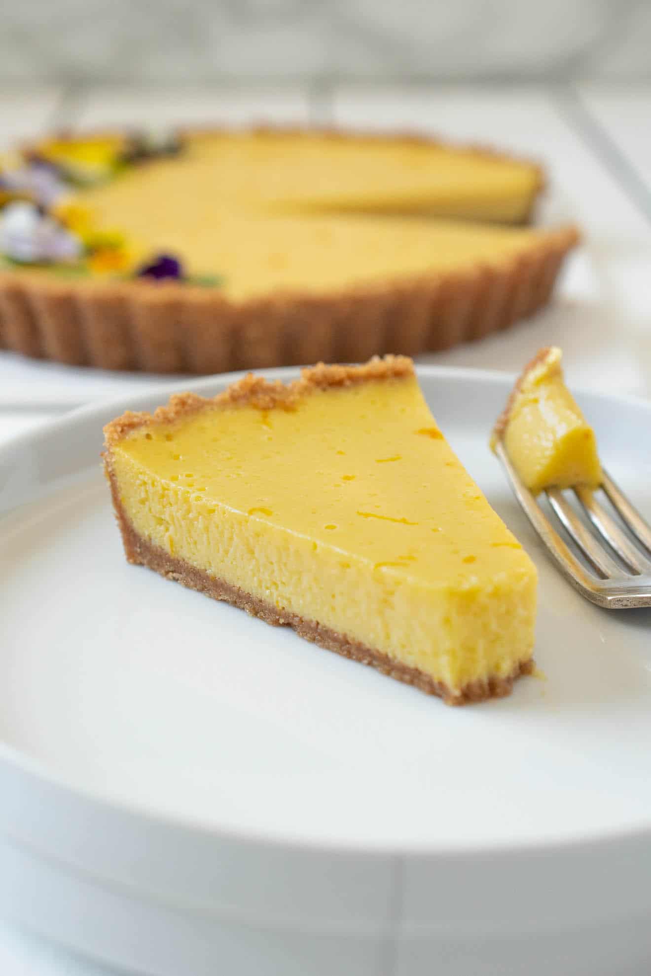 A slice of mango pie on a white plate with some on a fork