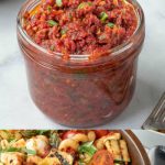 A jar of pesto and a vegetable pasta salad