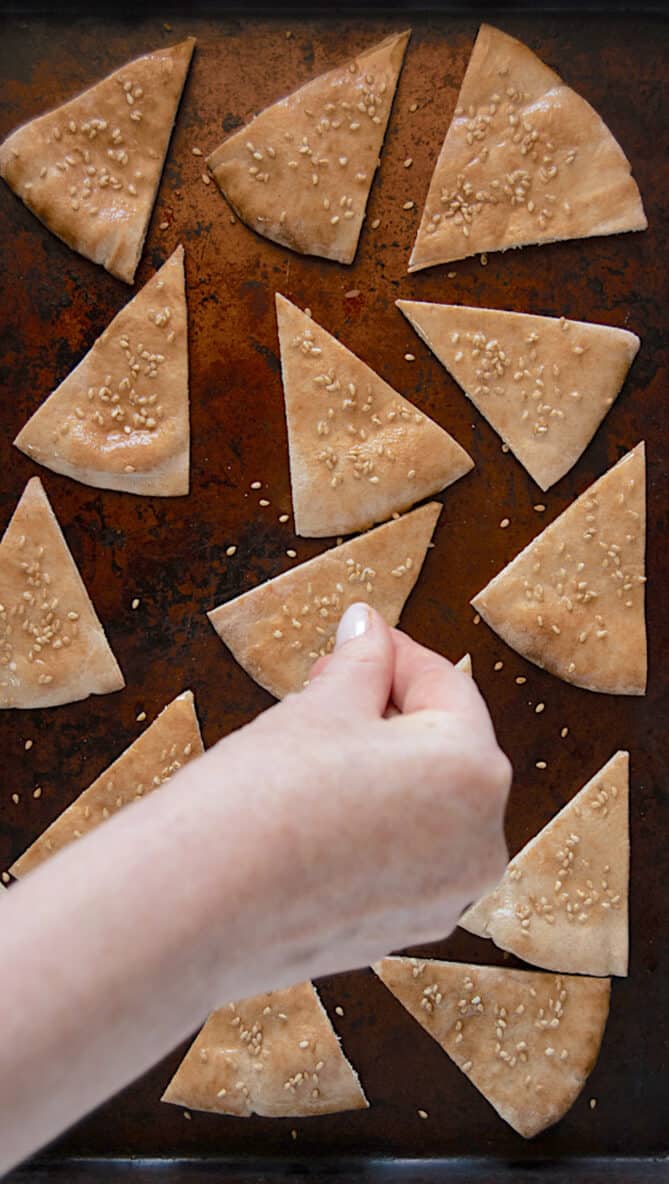 Sprinkling sesame seeds over toasted pita chips