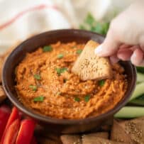 Using a pita chip to scoop up hummus