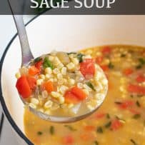 A ladle full of soup with corn and red peppers