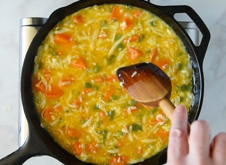The frittata mix in a cast iron skillet being stirred before baking