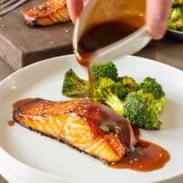 Pouring teriyaki sauce over cooked salmon