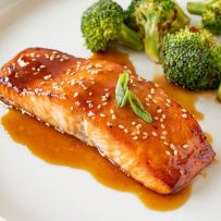 Teriyaki Glazed Salmon on a white plate with green onion and broccoli