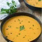 2 black bowls filled with bright orange butternut squash soup