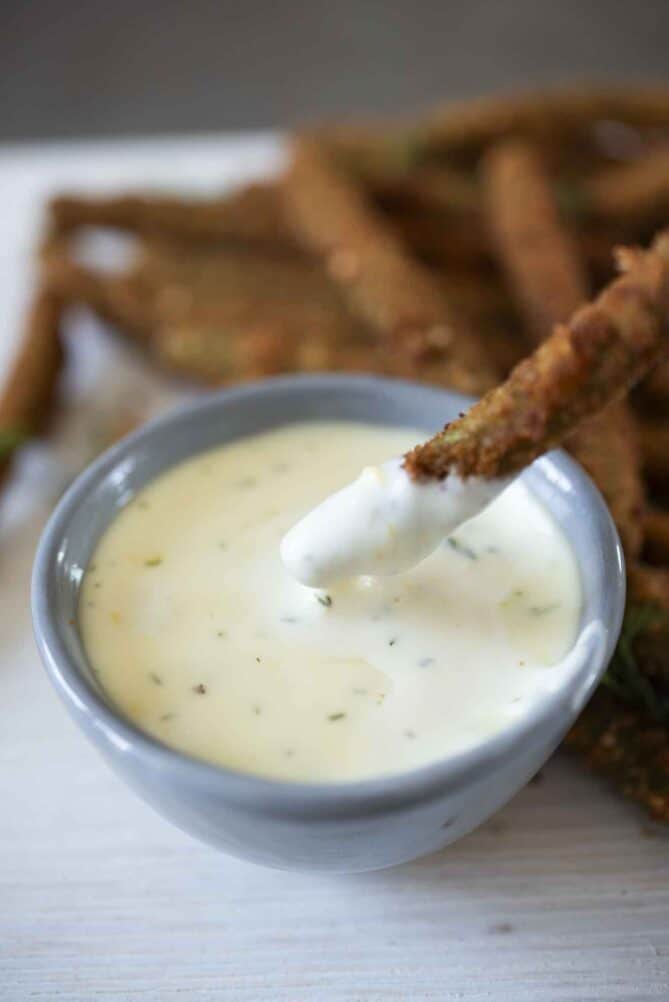 Dipping a fried green bean into a creamy lemon sauce