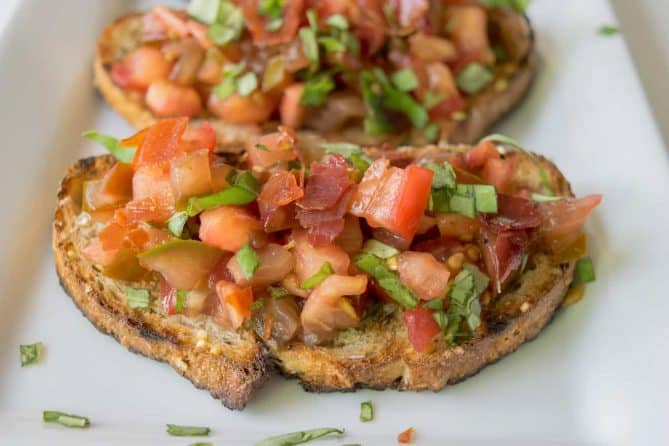A closeup of tomato bruschetta topped with crispy prosciutto