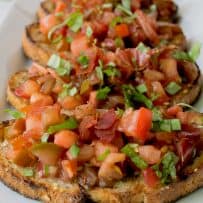Beautiful red tomatoes with green basil and crispy prosciutto on toasted bread slices