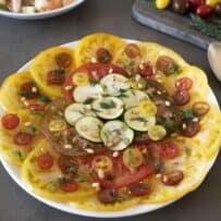 Sliced yellow and red heirloom tomatoes with sliced zucchini on a round plate