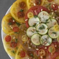A overhead view of tomato slices and zucchini slices in a pretty display