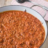 A large pan of Bolognese sauce with a ladle